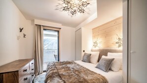 Une chambre moderne avec une tête de lit en bois, un grand plaid en fausse fourrure et une vue sur un balcon.