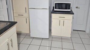 A compact kitchen with a white refrigerator, a microwave, and a small cabinet.