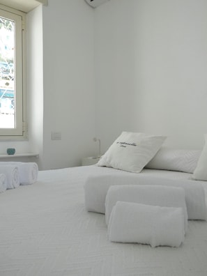 A minimalist bedroom with a bed, pillows, and a window.