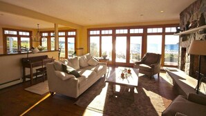 A spacious living room with large windows, a fireplace, and a view of the outdoors. - Pumpkin Point, 5BR Ocean Views, Dock (St George)