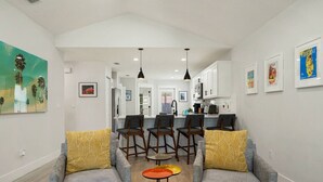 Ein modernes Wohnzimmer mit grauen Sofas, einem Couchtisch und einer Küche im Hintergrund.
