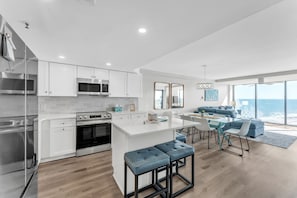 A modern kitchen with white cabinetry, stainless steel appliances, and a central island with bar stools.