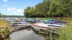 Un port de plaisance où de nombreux bateaux sont amarrés à des quais en bois, entouré d’arbres et de zones verdoyantes.