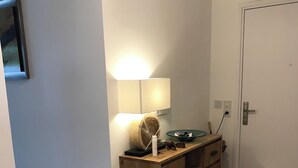 Un couloir avec une armoire en bois, une lampe fixée au mur et une porte.