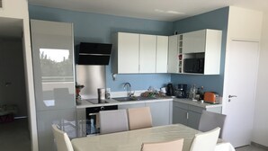 Une cuisine moderne avec des meubles blancs, un micro-ondes noir et un coin repas comprenant une table et des chaises.