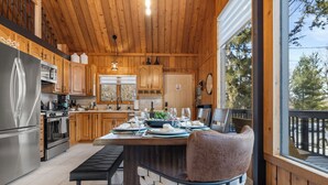 A modern kitchen with wooden cabinets, stainless steel appliances, and a dining area with a table set for two.