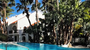 Une piscine entourée de palmiers et un bâtiment avec un toit rouge.