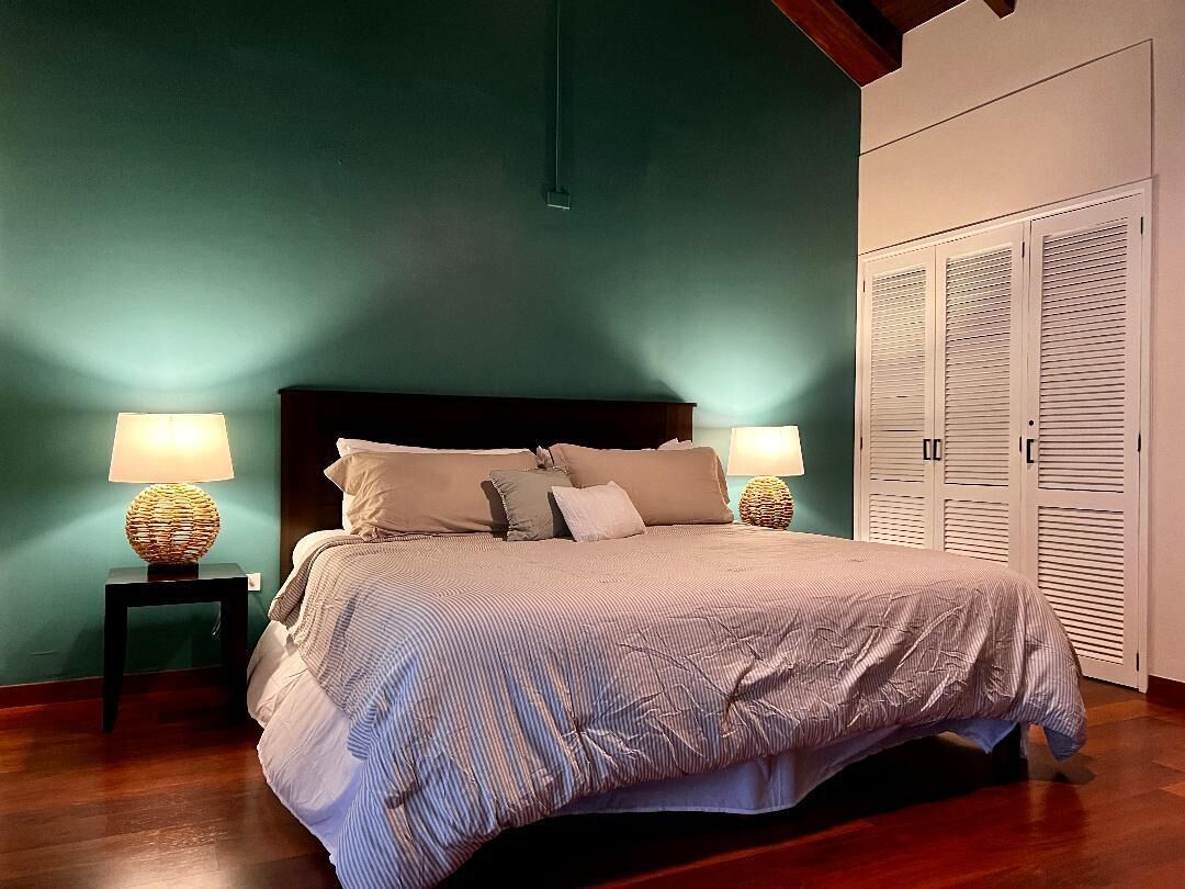 Un dormitorio con una cama, dos lámparas de noche, un cabecero y un armario.