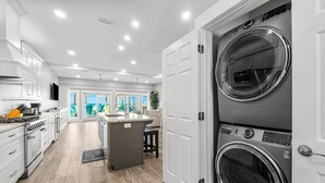 A modern kitchen with stainless steel appliances, a central island, and a view to a bright outdoor area.