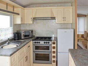 A compact kitchen with a gas stove, built-in oven, microwave, and a refrigerator. - 2 bedroom accommodation in Sandown (Sandown)