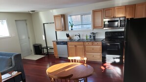 A modern kitchen with wooden cabinets, a black refrigerator, and a dishwasher. - Walkout Garden 1-bedroom  in Grande Prairie AC, WiFi, laundry, parking space (Grande Prairie)