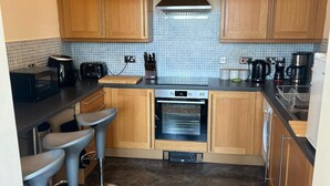 A modern kitchen with wooden cabinets, a built-in oven, a toaster, and a coffee maker. - Cardiff Apt - Sleeps 6 - Castle & Stadium Nearby (Cardiff)