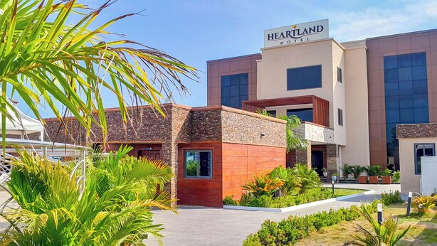 A HEARTLAND HOTEL with a modern design, featuring a stone facade, large windows, and a well-maintained garden area. - Heartland Hotel  (Ada)