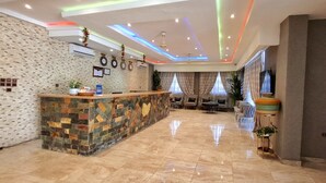 A hotel lobby with a reception desk, seating area, and decorative wall elements. - Heartland Hotel  (Ada)
