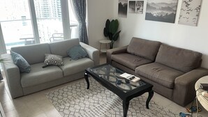 Un salon avec deux canapés, une table basse et une grande fenêtre.