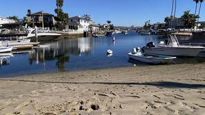A marina with boats docked, a sandy beach, and houses along the water.