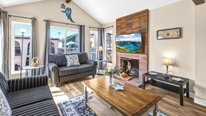 A living room with striped sofas, a wooden coffee table, a fireplace, and a large painting of a landscape.