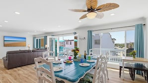 A dining area with a blue table, white chairs, and a ceiling fan.