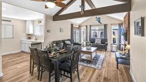 A spacious living area with a dining table set for four, a ceiling fan, and a fireplace.