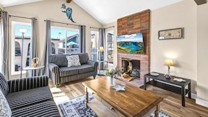 A living room with striped sofas, a wooden coffee table, a fireplace, and a large painting of a landscape.