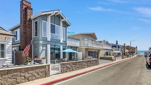 A coastal street with a row of houses, including a building with a blue facade and a stone wall.