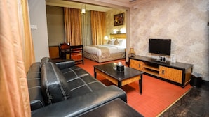 A hotel room with a sofa, a bed, a TV, a desk, and a red carpet. - CREEK GATE HOTEL (Sharjah)