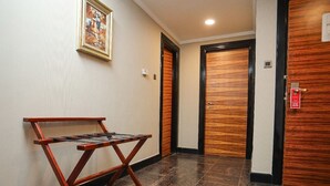 A hallway with patterned flooring, wooden doors, and a metal rack. - CREEK GATE HOTEL (Sharjah)
