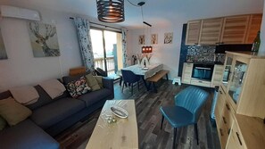 A modern living room with a sofa, dining table, and chairs. There is a kitchen area with cabinets and a countertop. - 250m from resort center, 3rd floor, view open, balcony, tv, ski locker, 55m², Valfréjus (Valfréjus)