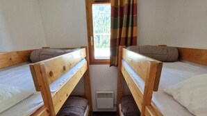 A small, narrow room with two wooden bunk beds, a window with curtains, and a visible air vent. - 30m from ski slopes, 5th floor, view open, balcony, tv, ski locker, 55m², Valfréjus (Valfréjus)