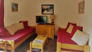 Um quarto aconchegante com duas camas de madeira, uma televisão e um armário de madeira.
