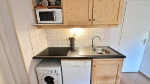 A compact kitchen with wooden cabinets, a microwave, a sink, and a dishwasher. - 30m from ski slopes, 3rd floor, view open, balcony, tv, ski locker, 42m², Valfréjus (Valfréjus)