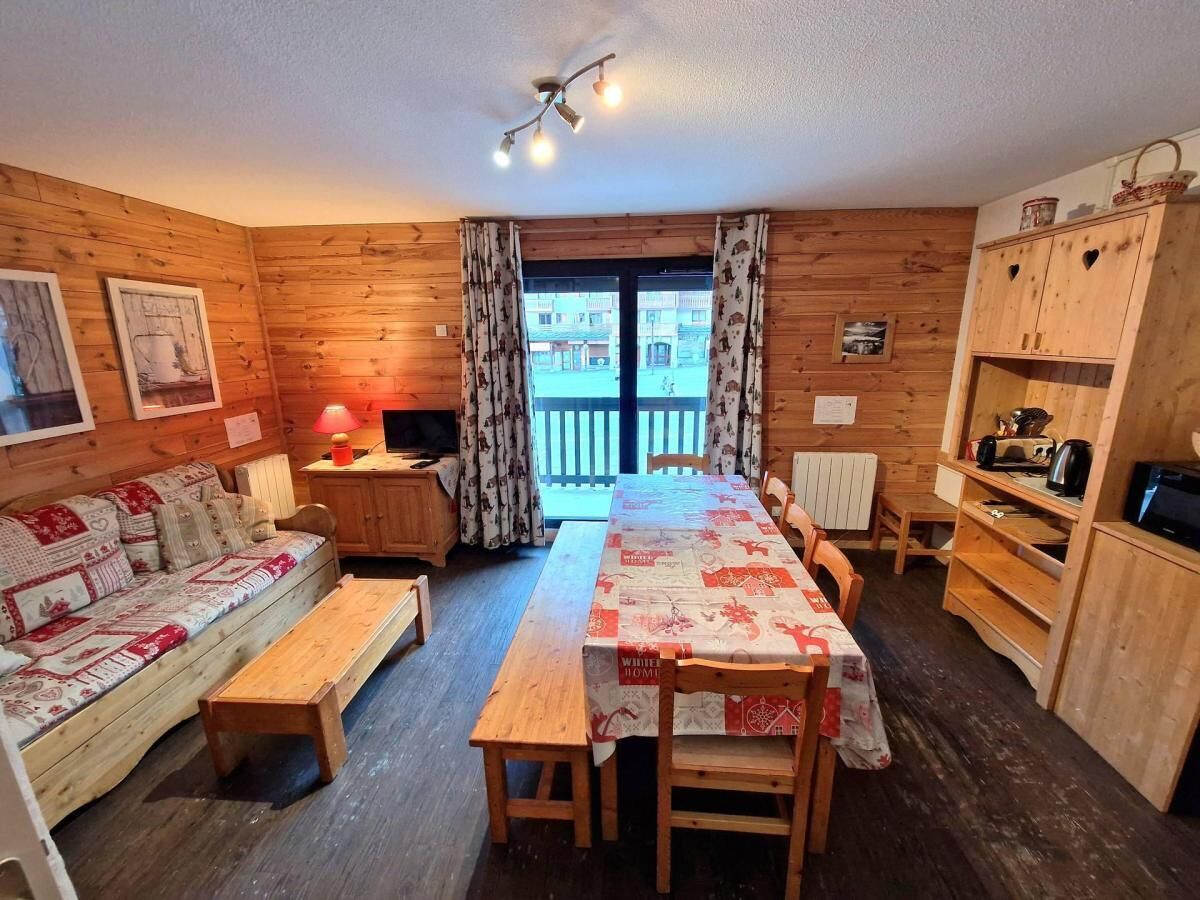 Ein gemütliches Blockhaus-Interieur mit einem Holzesstisch, Bänken, einer Couch und einer Küchenzeile mit Holzschränken und einem Herd.