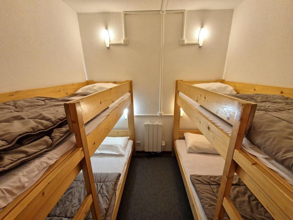 Habitació petita i senzilla amb dos llits búnquers, un radiador i llums penjades a la paret.