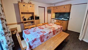 A compact kitchen with wooden cabinets, a dining table with a red and white tablecloth, and a small oven.