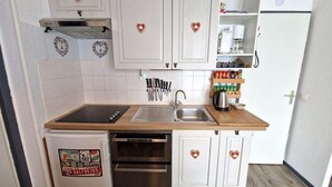 A compact kitchen with white cabinets, a stainless steel sink, and a built-in oven. - 30m from ski slopes, 1st floor, view mountain, balcony, tv, ski locker, 42m², Valfréjus (Valfréjus)