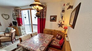 A cozy dining area with a wooden table and benches, a chandelier, and decorative wall art. - 30m from ski slopes, 1st floor, view mountain, balcony, tv, ski locker, 42m², Valfréjus (Valfréjus)