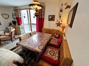 Uma área de refeições acolhedora, com uma mesa de madeira e bancos, um candelabro e arte decorativa na parede.