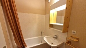 Een badkamer met een bad, een wastafel en een spiegel.