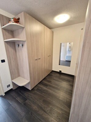 Ein Zimmer mit einem Holzschrank, einer kleinen Ablage mit Spielzeug und einem Spiegel an der Wand.