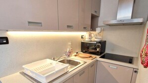 A compact kitchen with a sink, a coffee maker, and a stove.