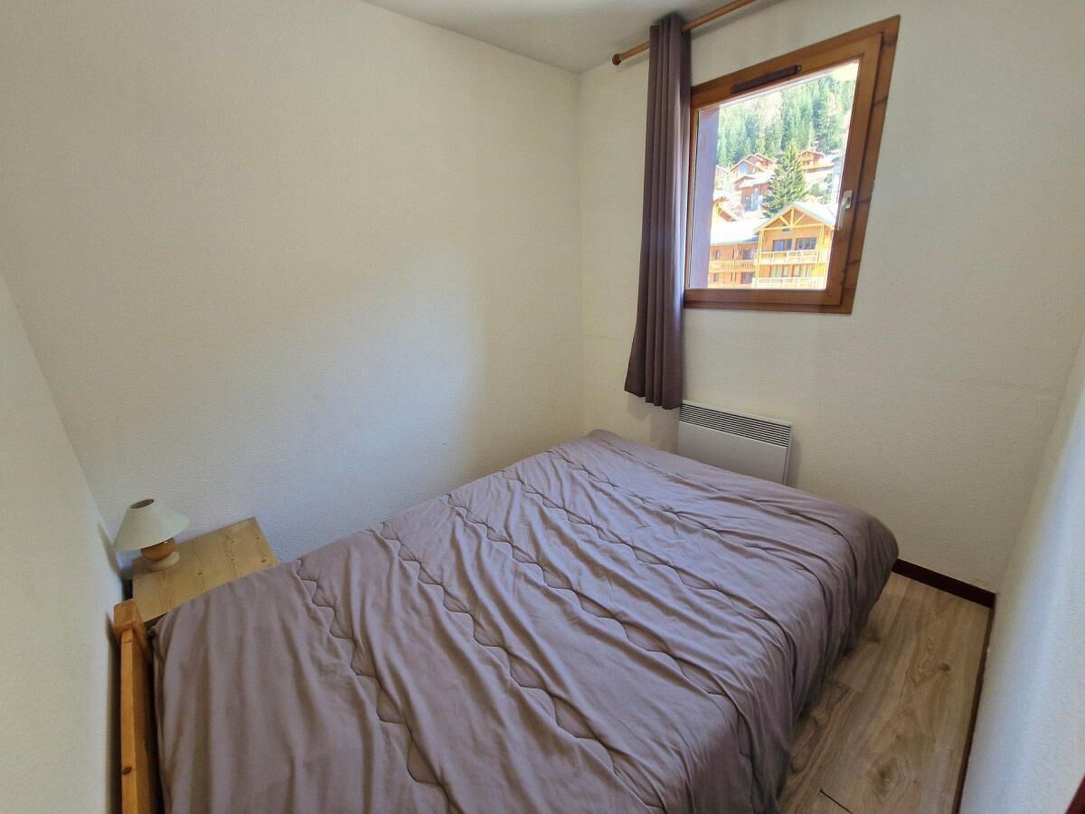 Una habitación pequeña con cama individual, ventana, radiador y suelo de madera.