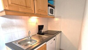 A compact kitchen with wooden cabinets, a stainless steel sink, a coffee maker, and a microwave. - 30m from ski slopes, 3rd floor, balcony, tv, ski locker, 32m², Valfréjus (Valfréjus)