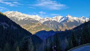 A mountainous landscape with snow-capped peaks, dense forest, and a paved road. - 30m from ski slopes, 3rd floor, balcony, tv, ski locker, 32m², Valfréjus (Valfréjus)