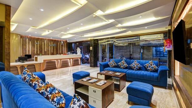 A modern hotel lobby with a reception desk, blue sofas, and a coffee table. - The York Legacy (New Delhi)