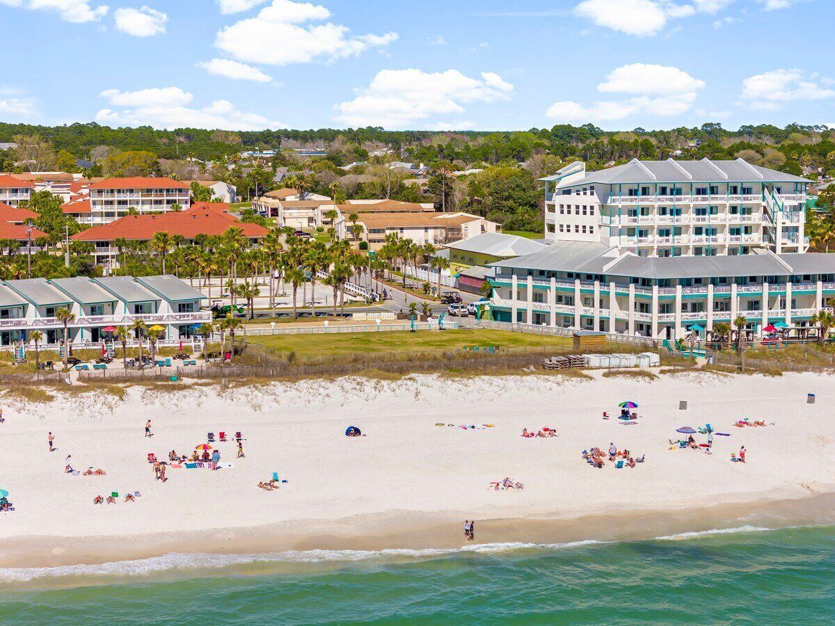 Ein Strandhotel mit mehreren Gebäuden, einem Sandstrand und Blick auf den Ozean.