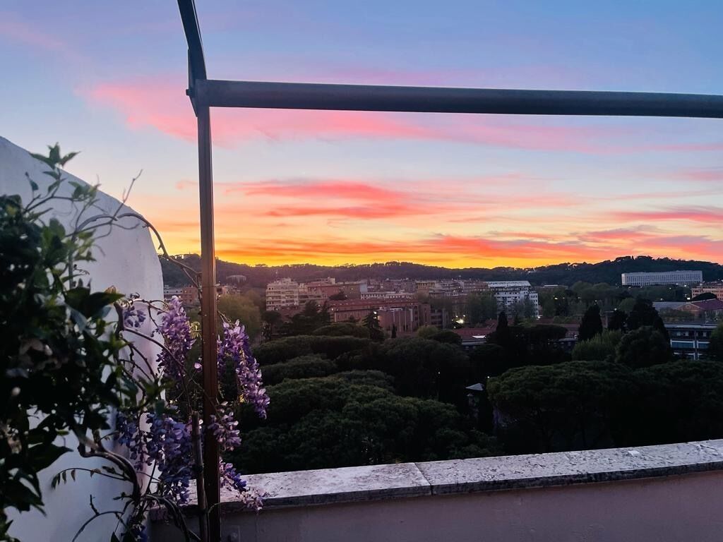 Un balcon offrant une vue sur le paysage urbain au coucher du soleil.