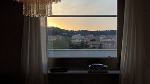 A room with a large window overlooking a cityscape at sunset. - Penthouse _ 70' Suite Gallery with Panoramic Terrace (Roma)