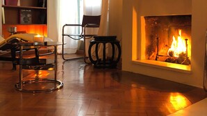 A cozy living room with a fireplace, a bookshelf, a chair, and a cowhide rug. - Penthouse _ 70' Suite Gallery with Panoramic Terrace (Roma)