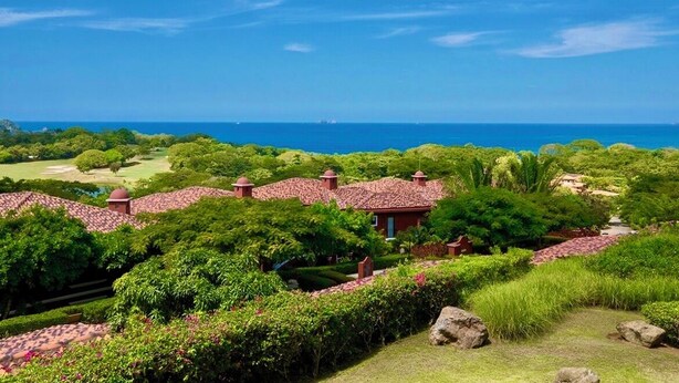 A coastal resort with terraced villas, lush greenery, and a view of the ocean. - 2-bedroom condo in Reserva Conchal, best ocean view!!! (Playa conchal)