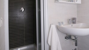 A modern bathroom with a glass-enclosed shower, a white sink, and a mirror above it. - Rooms Monteverde (Rome)